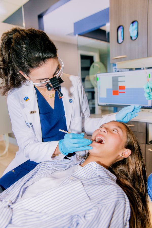 Photo of Dr. Mana inspecting a new patient's teeth at the dental clinic during a routine new patient consultation.