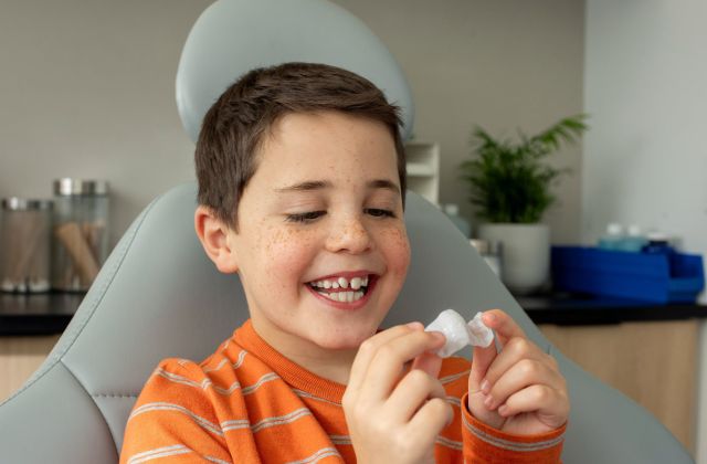 A photo of a young boy holding the Invisalign Palatal Expander in his hands. Dr. Mana Naeim at Serene Orthodontics offers Invisalign palatal expanders, traditional expanders, and removable expanders